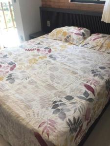 a bed with a floral comforter on it at Flat novo e estiloso na praia Ponta de Campina in Cabedelo