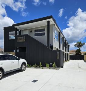 um carro branco estacionado em frente a uma casa preta em Redwood Apartments em Rotorua