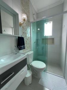 La salle de bains est pourvue de toilettes et d'une douche en verre. dans l'établissement Apartamento Residencial Alves Balneário Piçarras, à Balneário Piçarras