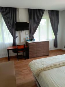 a bedroom with a bed and a desk and windows at NK Villa Syariah And Cafe Prigen in Pasuruan