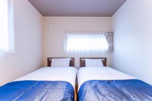 2 camas en una habitación pequeña con ventana en Stagione Hakone Yumoto Villa スタジオーネ箱根湯本VILLA, en Hakone