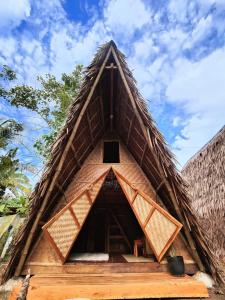 una casa con techo de paja y un cielo azul en el fondo en Wonderland en Siquijor