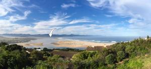 un aquilone che vola sopra una spiaggia e l'oceano di Chalet 40 Plettenberg Bay A tranquil location with beach access in large grounds ideal for families a Plettenberg Bay