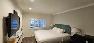 um quarto com uma cama e uma televisão de ecrã plano em Bay Front Inn em Santa Cruz