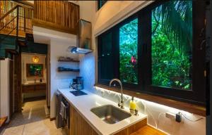 une cuisine avec un évier et une grande fenêtre dans l'établissement Condo VNV walking to Playa Guiones, à Nosara