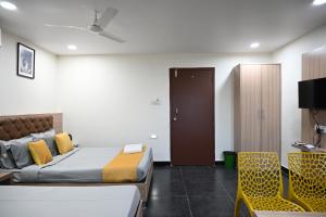 a bedroom with a bed and a door and a chair at Hotel Supraja Yellow Bells in Hyderabad