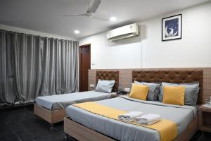 a bedroom with two beds with yellow and gray pillows at Hotel Supraja Yellow Bells in Hyderabad