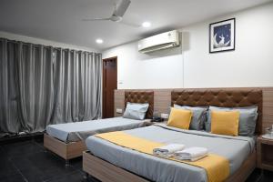 a bedroom with two beds with yellow and gray pillows at Supraja Cyber View in Hyderabad