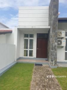 a white house with a brown door and grass at Bevons Place in Piliyandala