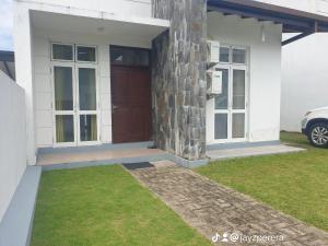 a white house with a brown door and grass at Bevons Place in Piliyandala +3 photos