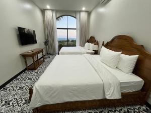 a hotel room with two beds and a window at Emirate Villa Mui Ne in Mui Ne