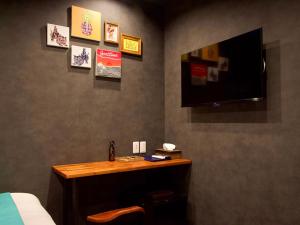 a bedroom with a desk and a tv on the wall at 杜屋 西表島 in Urauchi