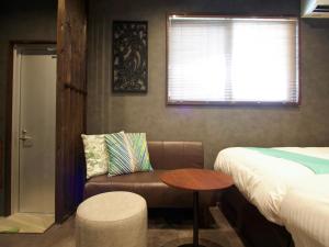 ein Schlafzimmer mit einem Bett, einem Stuhl und einem Tisch in der Unterkunft 杜屋 西表島 in Urauchi