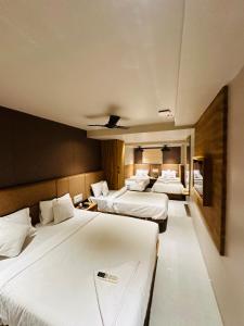 una camera d'albergo con tre letti con lenzuola bianche di HOTEL AMBER PARAMOUNT a Mumbai