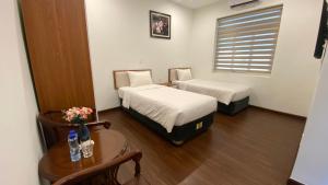 a room with two beds and a table and a window at Yên Tử Boutique Hotel in Yên Dương