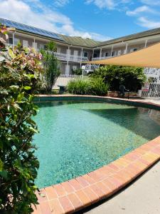 a large swimming pool in front of a building at Colonial Rose Motel in Townsville