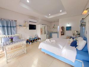 a bedroom with a large white bed and a tv at Prathana Garden Beach Resort in Hua Hin