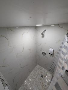 y baño con ducha y paredes de mármol blanco. en Green house, en Tampa