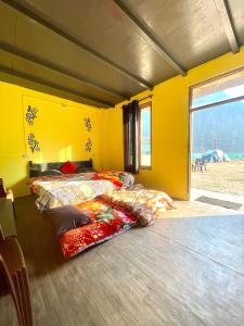 a bedroom with two beds in a yellow room at Damnbro Cafe & Stay KASOL in Kasol
