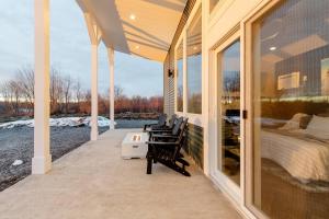 een afgeschermde veranda met een bed en 2 stoelen bij Luxurious Cabin on private 5 acres in Altmar
