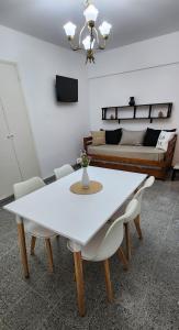 Depto de 2 ambientes zona Guemes (2) في مار ديل بلاتا: طاولة بيضاء وكراسي في غرفة بها سرير