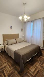 Un dormitorio con una cama grande y una lámpara de araña. en Depto de 2 ambientes zona Guemes (2) en Mar del Plata
