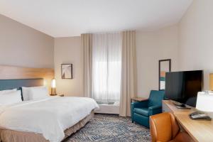 a hotel room with a bed and a television at Candlewood Suites Oklahoma City-Moore by IHG in Moore