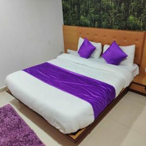een bed met paarse en witte lakens en kussens bij HOTEL GLOBLE in Vadodara