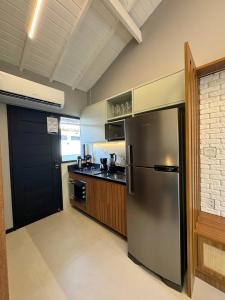 a kitchen with a stainless steel refrigerator and a stove at Apartamento studio novo e completo em Praia do Forte! 900m da Vila! in Praia do Forte