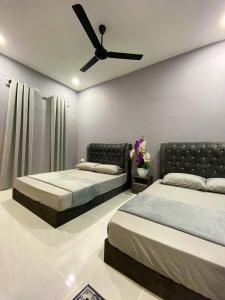 two beds in a bedroom with a ceiling fan at Roomstay Kak Ton in Kuala Terengganu