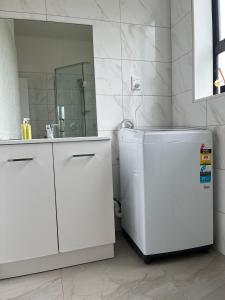 a white kitchen with a sink and a refrigerator at Totara Vale, Free Coffee, parking and wifi, near Glenfield Mall and highway 18,1 in Auckland