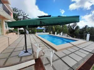 a large green umbrella sitting next to a swimming pool at Maison De Gloria in Locsin