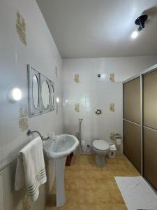 Baño blanco con lavabo y aseo en Casa Florianópolis, en Florianópolis
