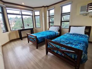 two beds in a room with windows at Crosswinds Tagaytay Three Bedroom Suite in Tagaytay