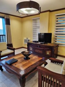 a living room with a wooden table and a flat screen tv at Crosswinds Tagaytay Three Bedroom Suite in Tagaytay