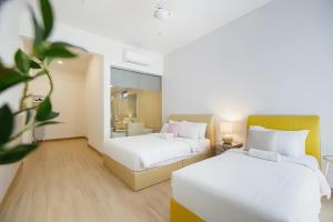 2 bedden in een hotelkamer met witte lakens bij Jazz Service Suite Penang in Tanjong Tokong