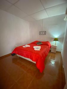 uma cama vermelha num quarto branco com um cobertor vermelho em Casa Candiotti em Paraná