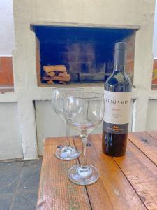 uma garrafa de vinho e dois copos de vinho numa mesa de madeira em Casa Candiotti em Paraná