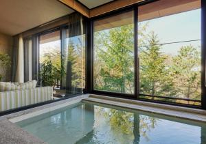 an indoor pool in a house with large windows at Fufu Karuizawa Yokou No Kaze in Karuizawa