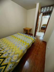 Schlafzimmer mit einem Bett mit gelber und blauer Decke in der Unterkunft Amplio Departamento en 2do piso in Cajamarca