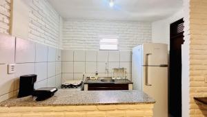 a small kitchen with a refrigerator and a counter at Suítes Bosque de Flecheiras in Flecheiras
