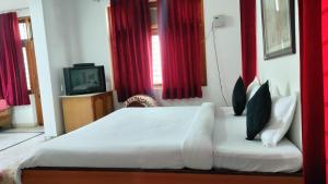 sypialnia z białym łóżkiem z czerwonymi zasłonami w obiekcie Jhalana Resort & pool party w mieście Dżajpur