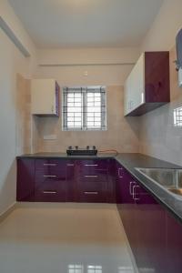 a kitchen with purple cabinets and a sink at HomeSlice Whitefield - 1BHK/ 2BHK Apartment/ Studio Room in Bangalore