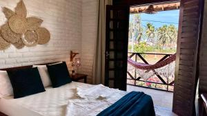 a bedroom with a bed and a large window at Suítes Bosque de Flecheiras in Flecheiras
