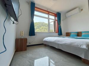 a bedroom with a bed and a window at Gubeikou Great Wall Juxian Residents' Lodging in Miyun