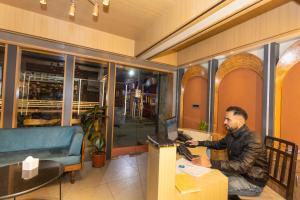 a man sitting at a desk using a laptop at Ananta Home in Kathmandu