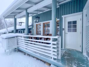 a house with a snowy porch and a white door at Spacious 2BD and Balcony apartment by the lake, free wifi in Ruka