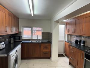 cocina con armarios de madera, fregadero y lavavajillas en Comfortable Single Room Wembley Park/Stadium, en Londres