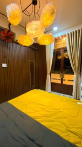 a bedroom with a yellow bed and chandeliers at SKY Homestay in Ấp Ðại Tài (2)