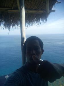 een man die zijn tanden poetst voor de oceaan bij Eco Tourist Dream Stay Tree House in Nusa Penida